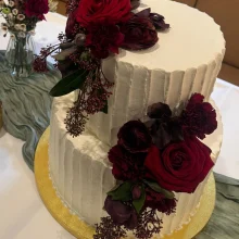 Zweistöckige Cremetorte mit dunkelroten Rosen